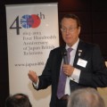 photo of Martin Barrow with microphone speaking in front of Japan400 banner